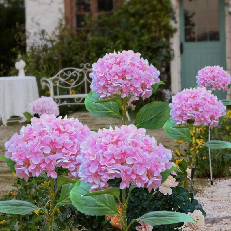 Pink hydrangea stake lights beside a garden chair in daylight — Casa Norex