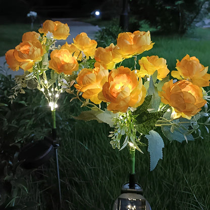 Orange and yellow peony stake lights glowing in a dark garden — Casa Norex