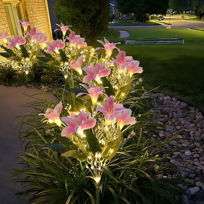 Pink lily stake lights lining a flower bed at dusk — Casa Norex