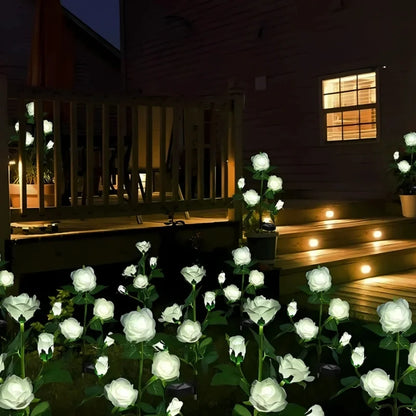 White rose stake lights glowing beside garden steps at night — Casa Norex