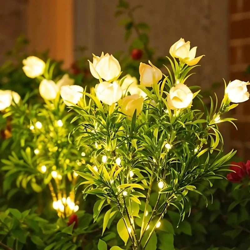 Yellow rose stake lights glowing in a garden at night — Casa Norex