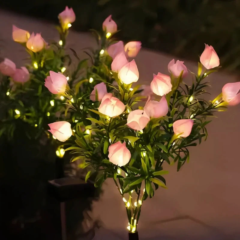 Pink rose stake lights with a warm glow on a patio at night — Casa Norex