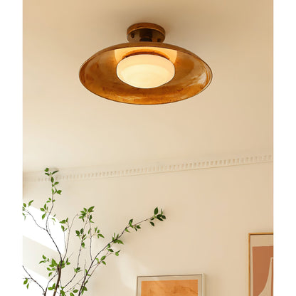 Gilded iron ceiling light seen from below beside a green plant — Casa Norex