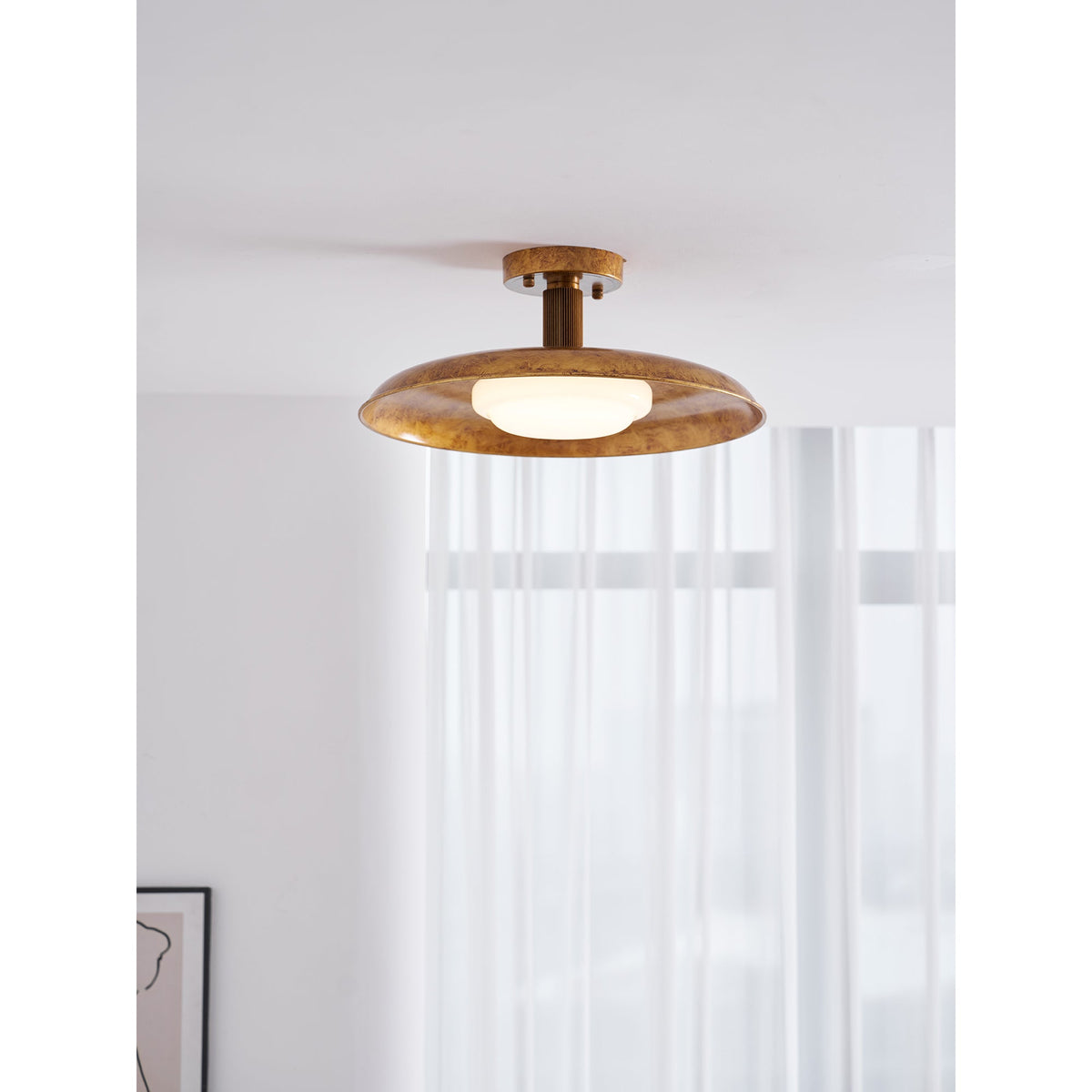 Gilded iron ceiling light lit above a wall with sheer curtains — Casa Norex