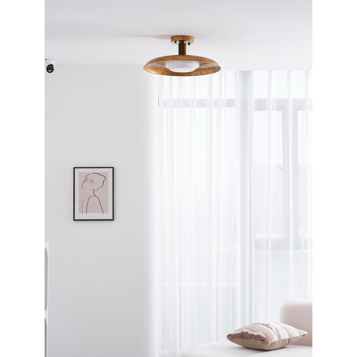 Gilded iron ceiling light in a room with a print and curtains — Casa Norex