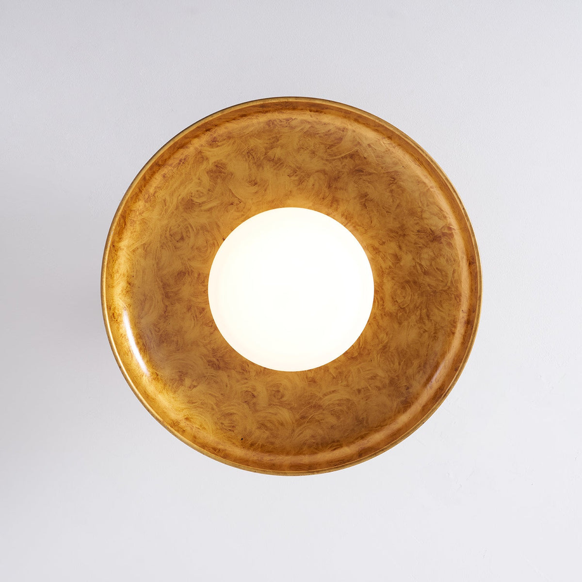 Gilded iron ceiling light seen from directly below, lit — Casa Norex