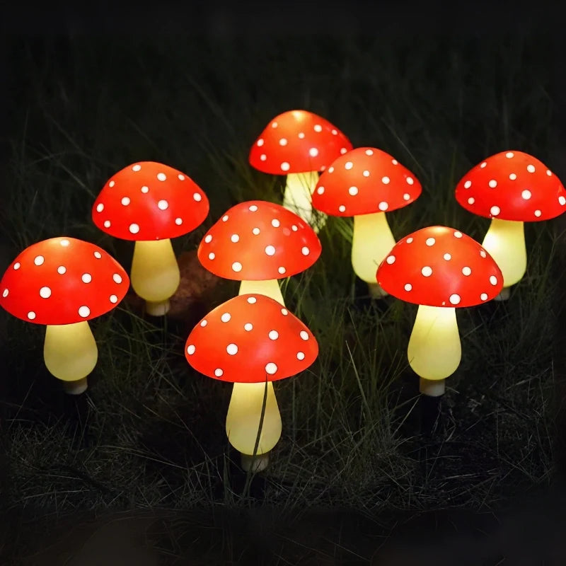 Red spotted mushroom stake lights glowing warm white in a dark garden | Casa Norex