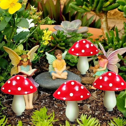 Red mushroom lights beside fairy garden figurines in a planted bed — Casa Norex