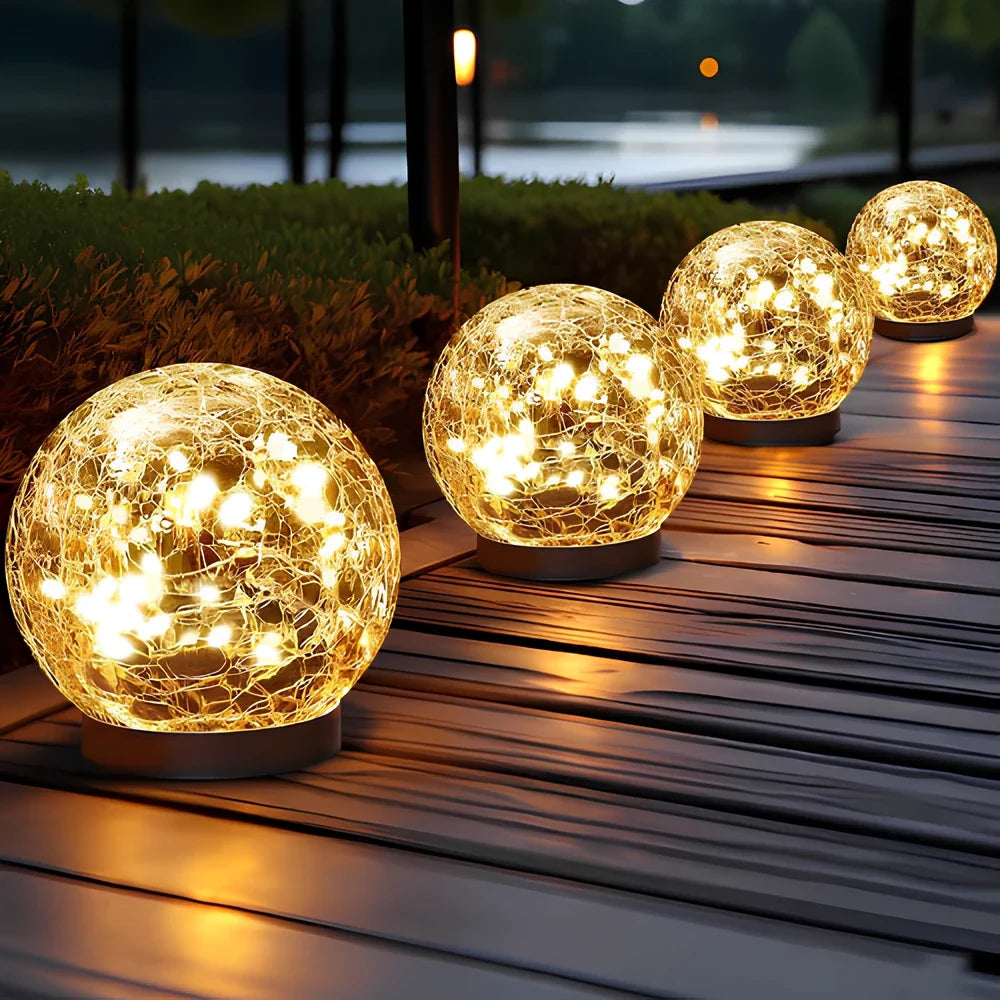 Solar landscape lights — cracked glass globes glowing warm white on a wooden deck | Casa Norex