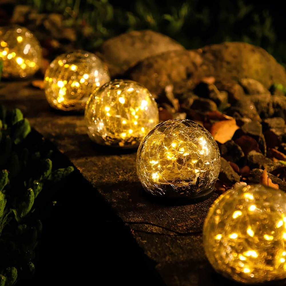 Row of solar glass globes lighting a garden path among rocks | Casa Norex