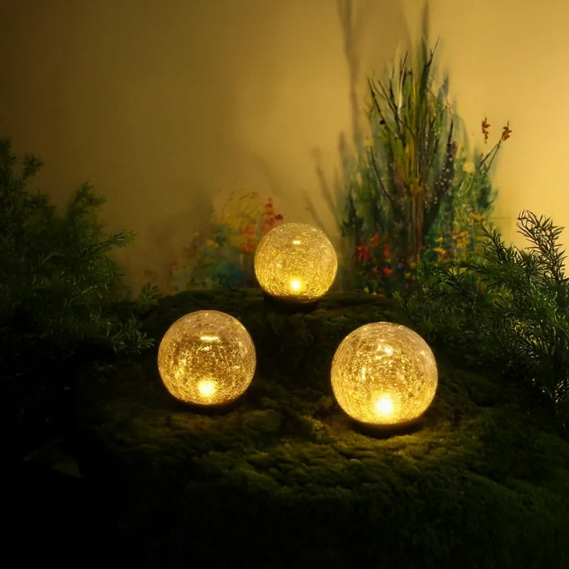 Two solar globe lights glowing in a garden bed at dusk — Casa Norex