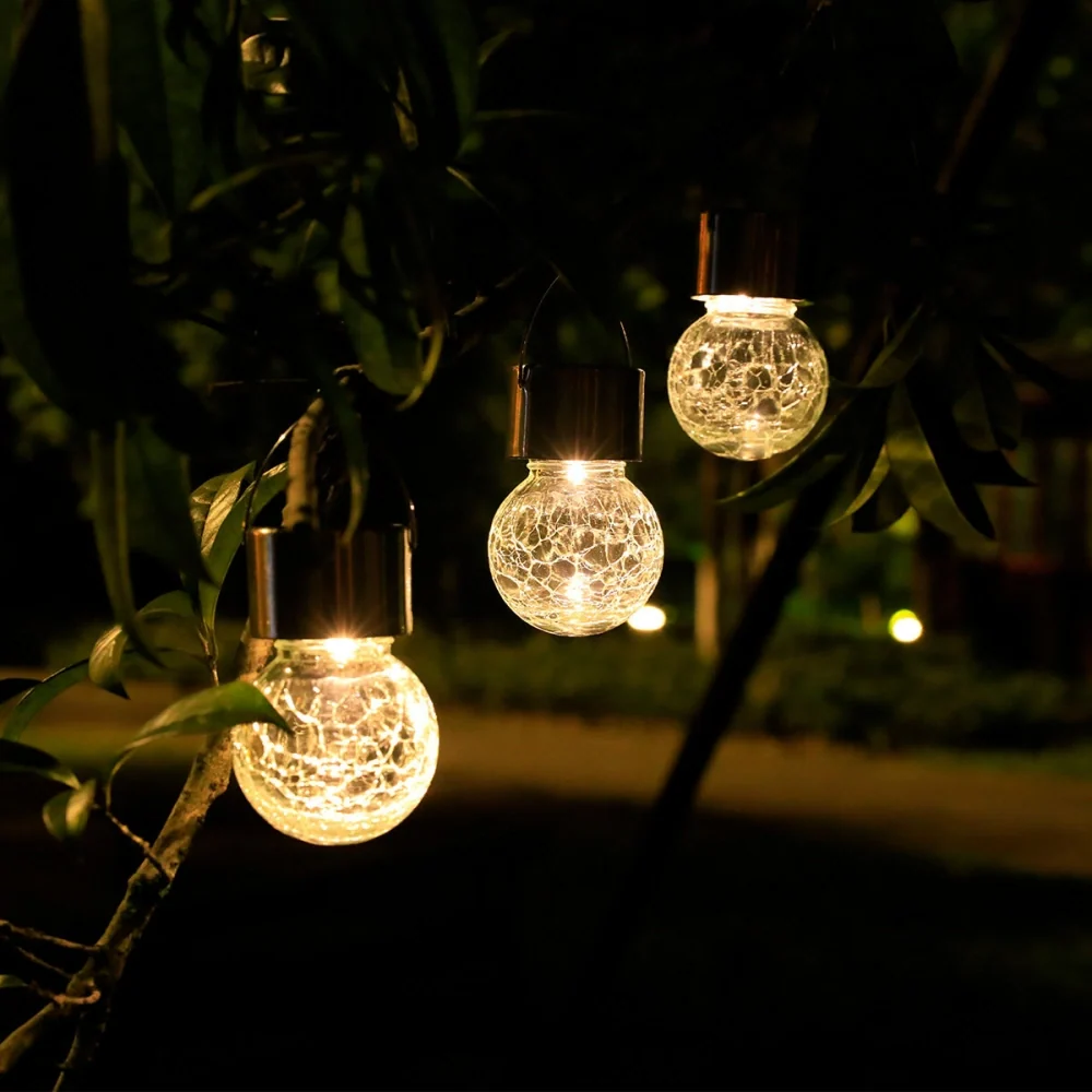Solar crackle glass lantern trio hanging in a garden tree and glowing at dusk | Casa Norex