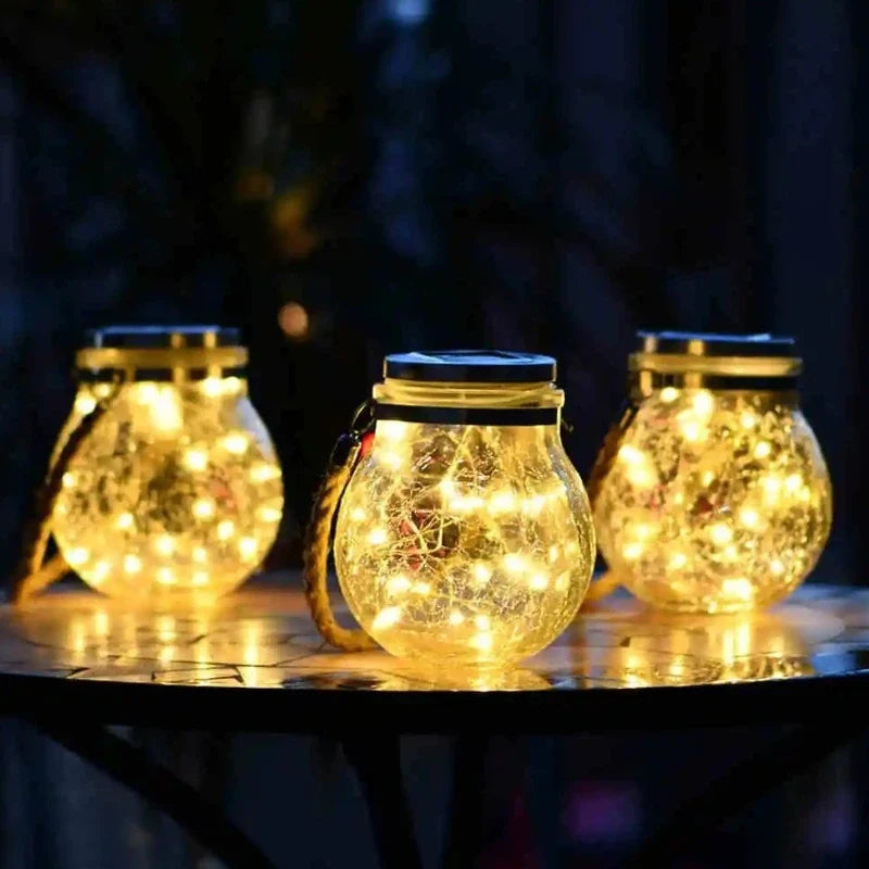 Three crackle glass lanterns glowing on a table at night — Casa Norex