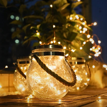 Large crackle glass lantern with a black handle among smaller lanterns on a table — Casa Norex