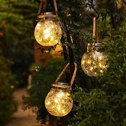 Three rope-handled lanterns hanging from garden branches — Casa Norex