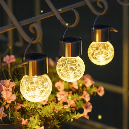 Glowing lanterns hanging from a scrollwork bracket beside pink flowers — Casa Norex