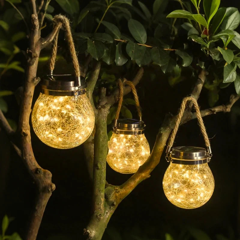 Rope-handled lanterns glowing in a leafy garden tree — Casa Norex