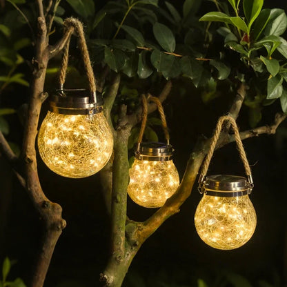 Rope-handled lanterns glowing in a leafy garden tree — Casa Norex