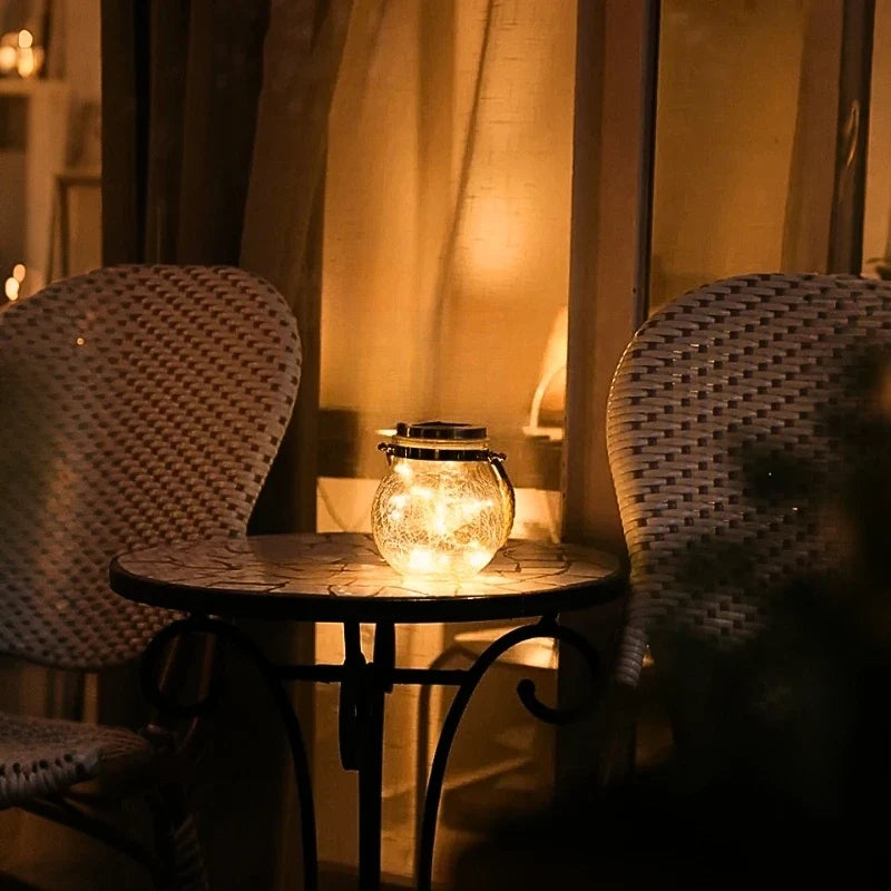 Crackle glass lantern glowing on a cafe table between two chairs — Casa Norex