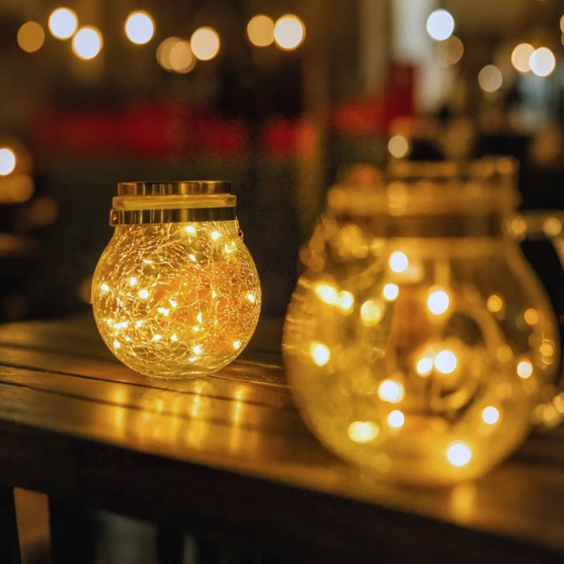 Large and medium crackle glass lanterns glowing side by side on a table — Casa Norex