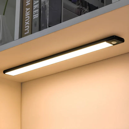 Black motion sensor light bar under a shelf above books | Casa Norex