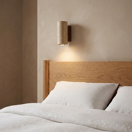 Wall sconce in bedroom setting — warm LED glow through stone-look shade | Casa Norex