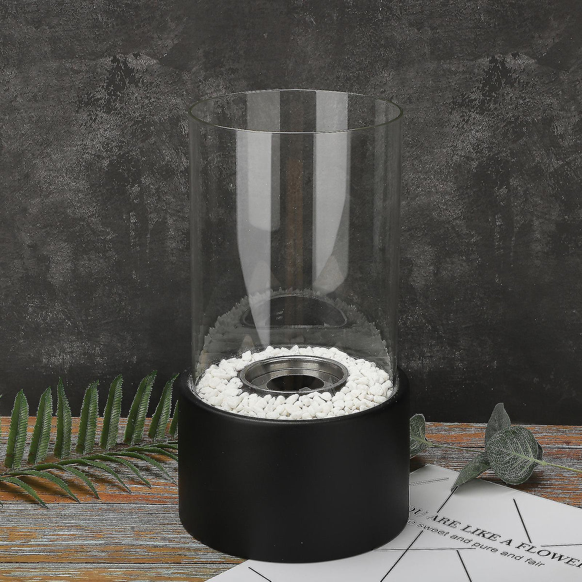 Black oil lamp on a dark patio surface surrounded by pebbles — Casa Norex