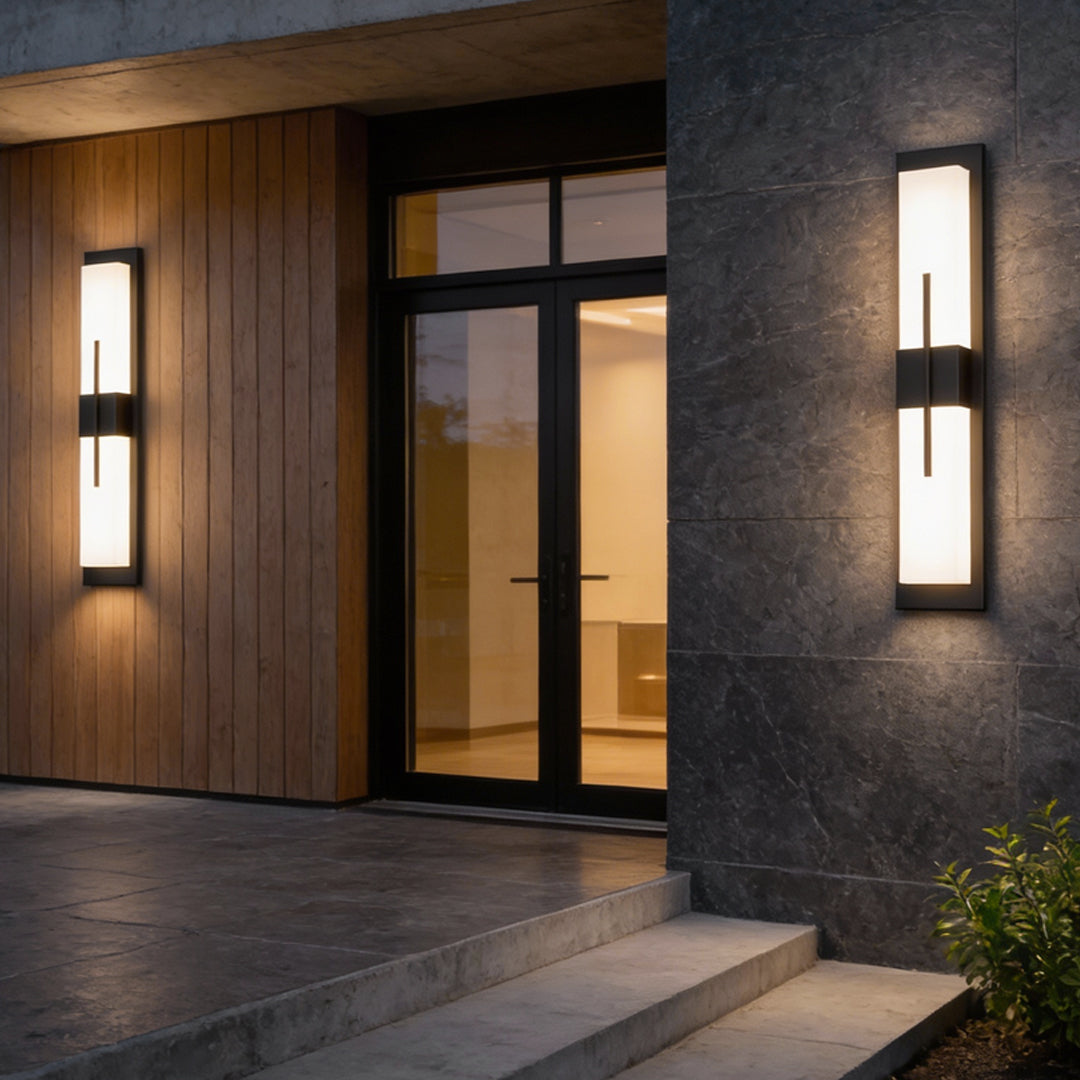 Tall rectangular outdoor wall light with warm light beside wooden door and stone wall — Casa Norex