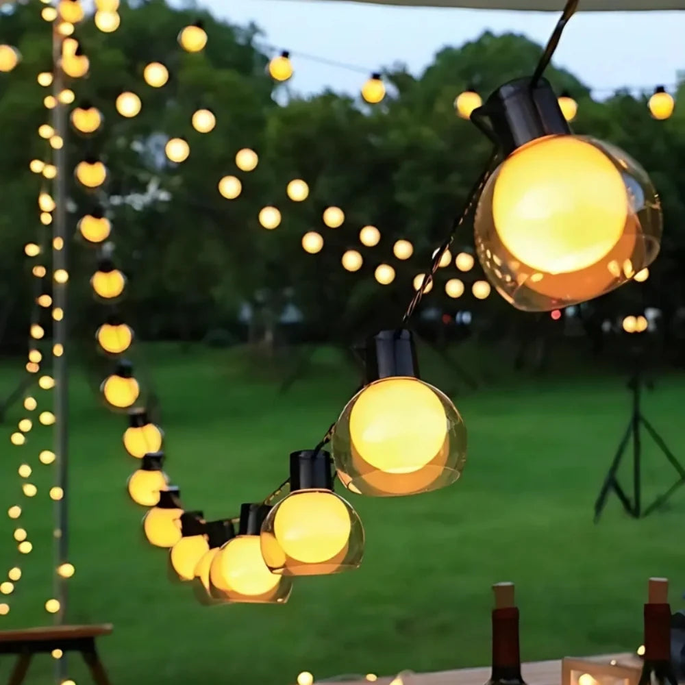 Solar string lights — warm globe bulbs strung across a lawn at dusk | Casa Norex