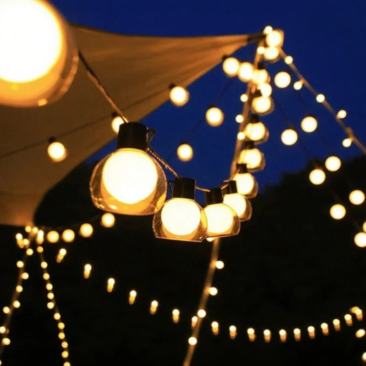 Solar globe string lights glowing over a garden under a night sky | Casa Norex