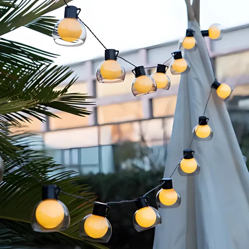 Globe string lights beside a white tent against a pale sky — Casa Norex