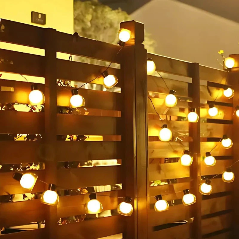 Solar string lights along a wooden fence at night — Casa Norex