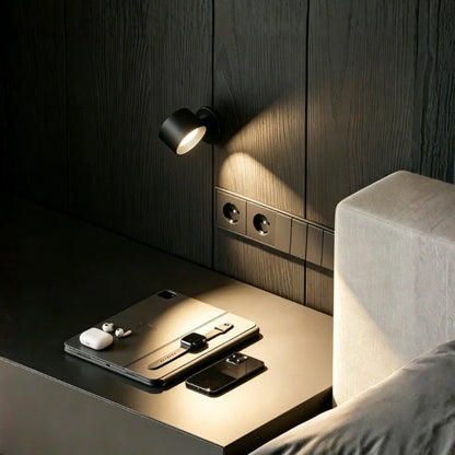 Black cordless wall lamp on a dark panel wall above a bedside table | Casa Norex