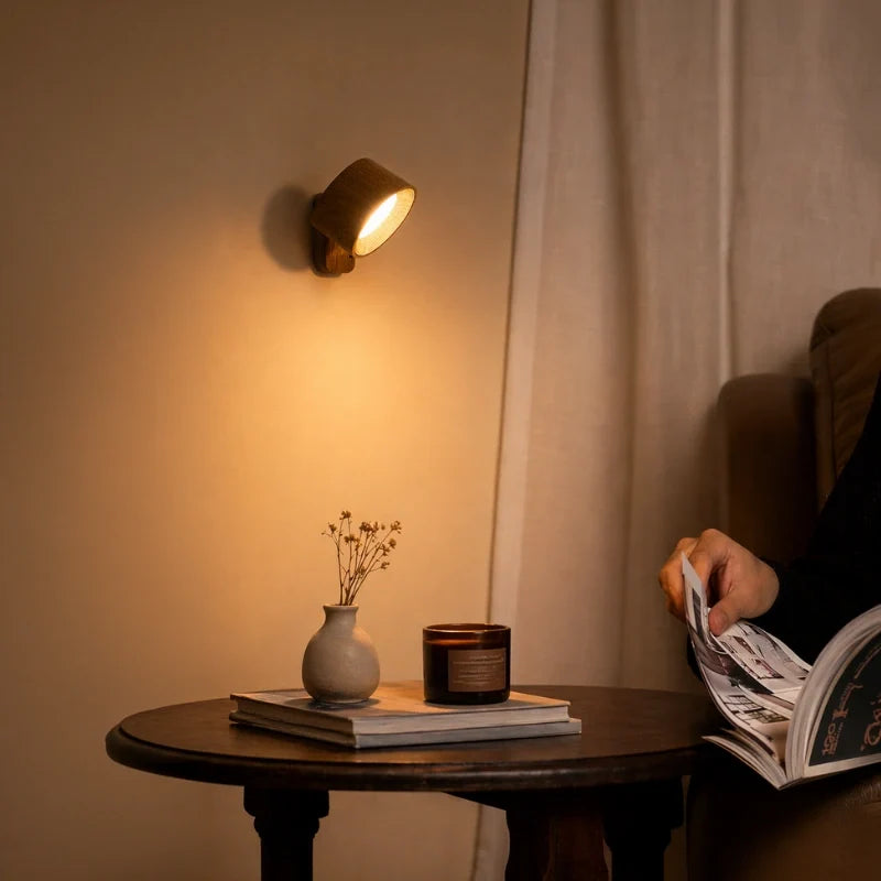 Wood-finish cordless wall lamp beside a curtain over a round side table | Casa Norex