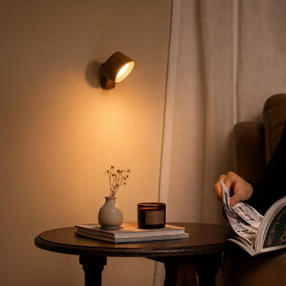 Wood-finish cordless wall lamp beside a curtain over a round side table | Casa Norex