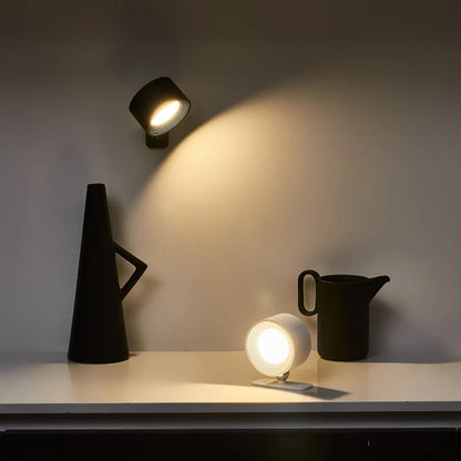 Black cordless wall lamp above a black jug and a small lamp on a shelf — Casa Norex