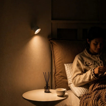 Person reading in bed beside a cordless wall lamp — Casa Norex
