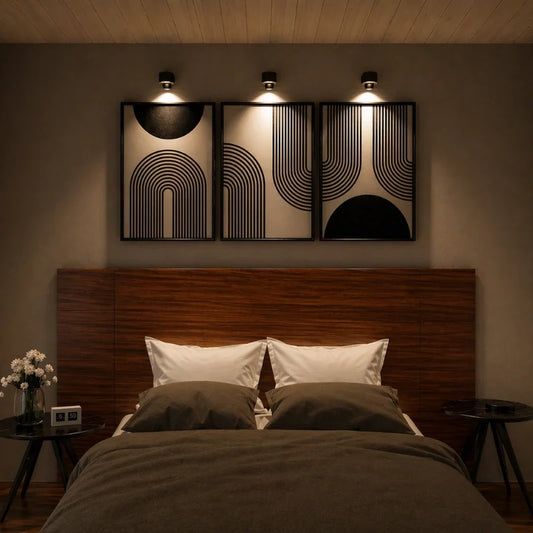 Three cordless wall lamps above framed art over a bed — Casa Norex