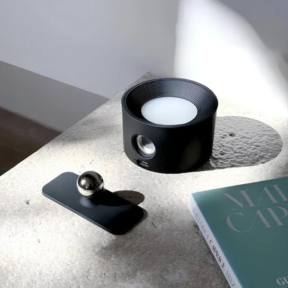 Black lamp lifted off its magnetic mount plate on a book — Casa Norex