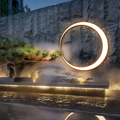 Round outdoor wall light above stone and water landscape — Casa Norex