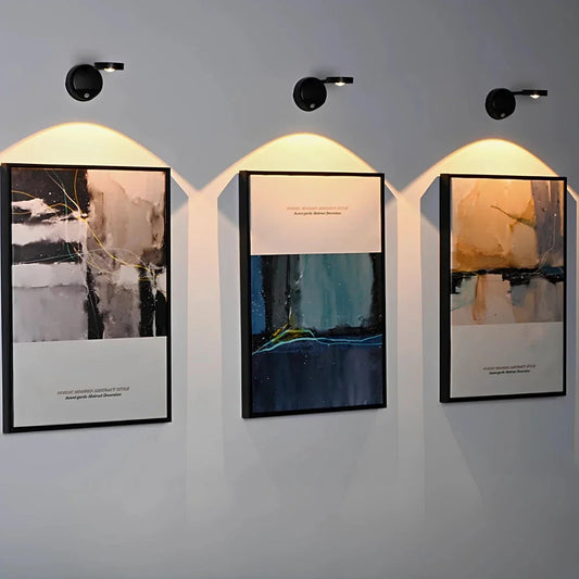 Black cordless picture light spotlights above three framed abstract paintings | Casa Norex