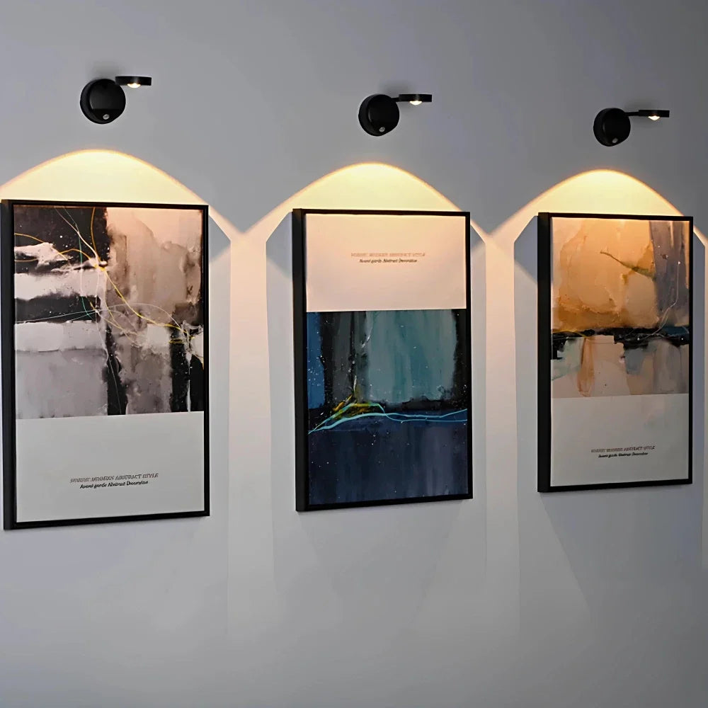 Black cordless picture light spotlights above three framed abstract paintings | Casa Norex