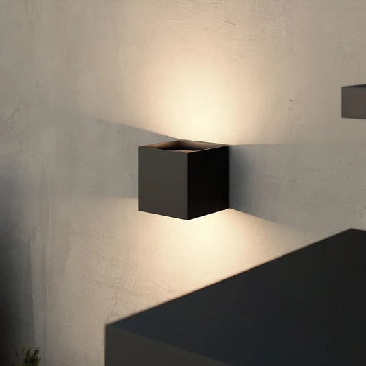 Black up-down cube outdoor wall light casting light on a gray wall | Casa Norex