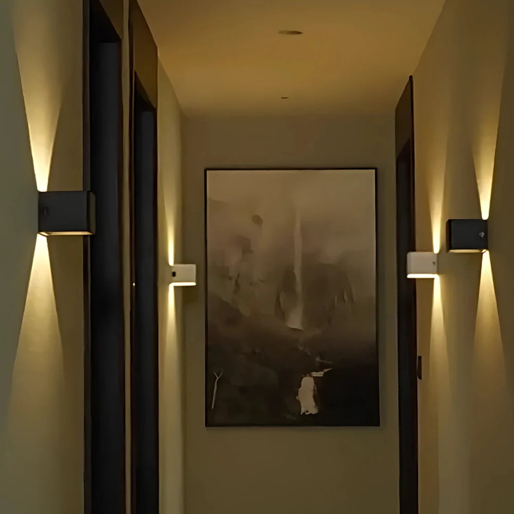 Two cube wall lights lighting a hallway beside framed art | Casa Norex