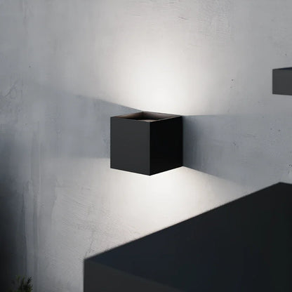 Black cube wall light close-up on a textured gray wall | Casa Norex