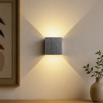 Brushed silver cube wall light beside a vase and framed art — Casa Norex