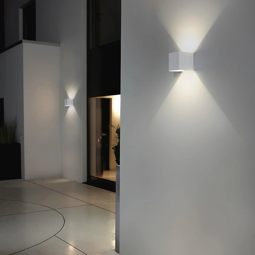 White cube wall light on a stucco corner at night — Casa Norex