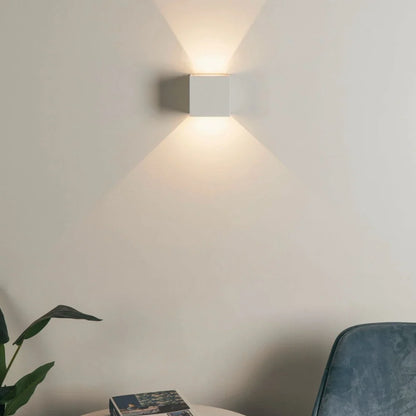 White cube wall light near an armchair and plant — Casa Norex