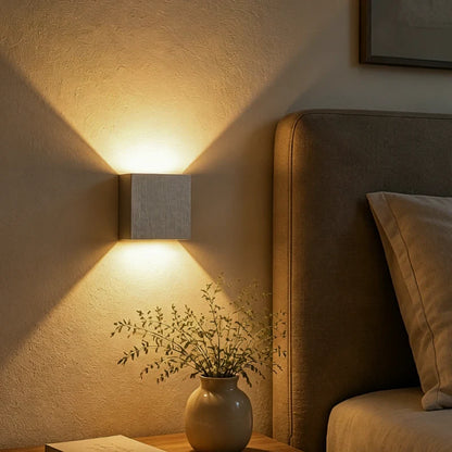 White cube wall light above a bed headboard with a warm glow — Casa Norex