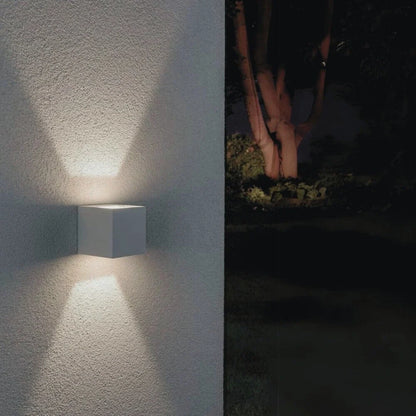 White cube wall light with a wide beam on a stucco wall at night — Casa Norex